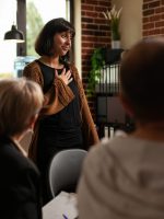Impressed woman receiving applause from group of people at aa meeting program Impressed woman receiving applause from group of people at aa meeting program. Therapy session patients clapping hands and celebrating achievement, showing support to joyful person.